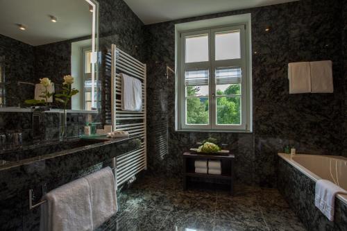 a bathroom with a tub and a sink and a window at Residenz Itterbach in Willingen