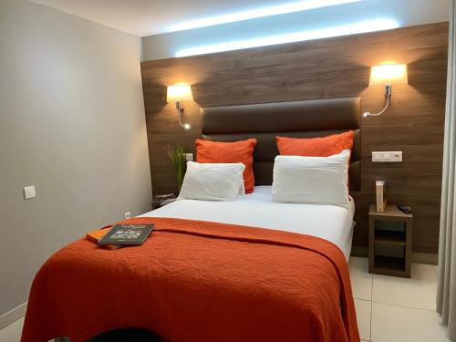 a bedroom with a large bed with an orange blanket at Hôtel Clairefontaine in Paris
