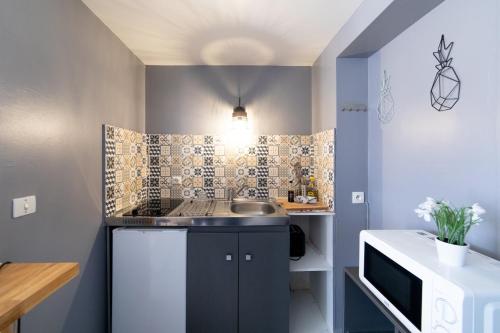 Elle comprend une petite cuisine avec un évier et un mur en carrelage. dans l'établissement LE CARRÉ MATABIAU HYPERCENTRE GARE NETFLIX, à Toulouse