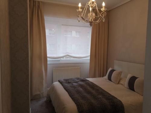a bedroom with a bed with a chandelier and a window at Habitación con baño privado en Bilbao in Bilbao