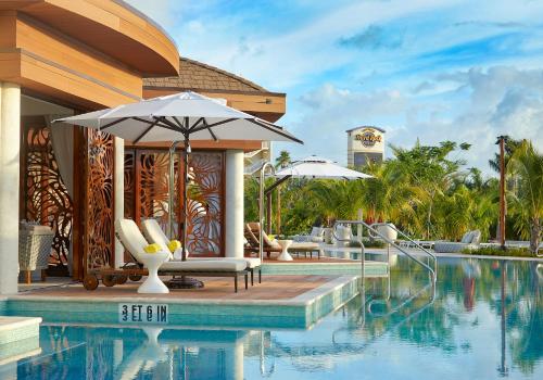 a pool at a resort with an umbrella and chairs at The Guitar Hotel at Seminole Hard Rock Hotel & Casino in Fort Lauderdale