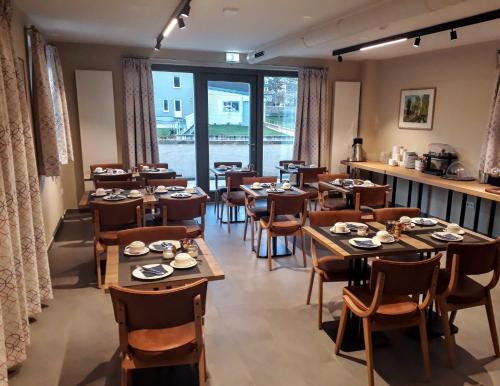 a restaurant with tables and chairs and a large window at Péitche Lauer in Useldange
