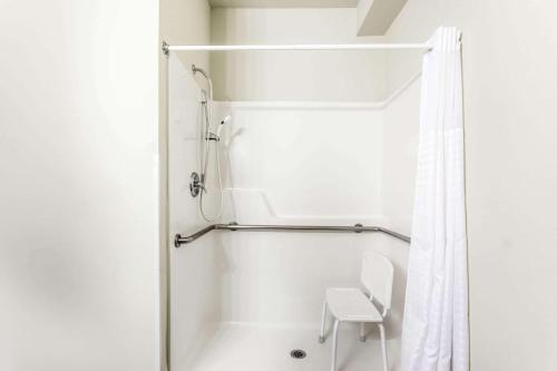 a white bathroom with a shower and a white chair at Days Inn by Wyndham Ellensburg in Ellensburg