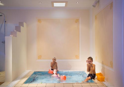 duas crianças estão sentadas numa piscina em Alpen Hotel Post em Au im Bregenzerwald