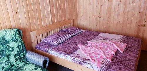 a bed in a wooden room with a chair at Marichka in Yablunytsya