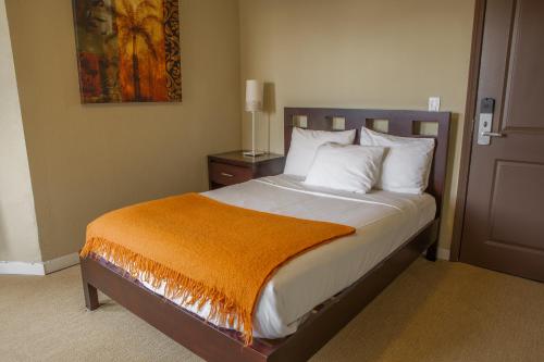 فندق كازا لوما في سان فرانسيسكو: غرفة نوم مع سرير مع بطانية برتقالية عليه
