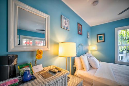 a bedroom with blue walls and a bed and a table at Seascape Tropical Inn in Key West