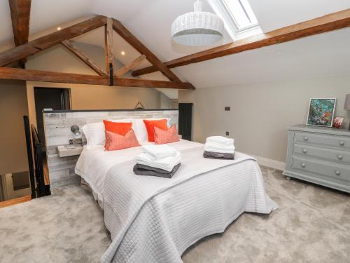 una camera da letto con un grande letto bianco con cuscini arancioni di The Old Workshop a Denbigh
