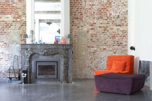 sala de estar con chimenea y silla naranja en Maison Mathilde en Valenciennes