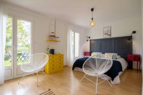 1 dormitorio con 1 cama y 2 sillas blancas en Ty Coz Breizh, en Guidel