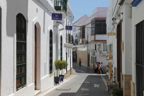 una calle con edificios blancos y gente caminando por ella en Apartamento céntrico Conil, en Conil de la Frontera