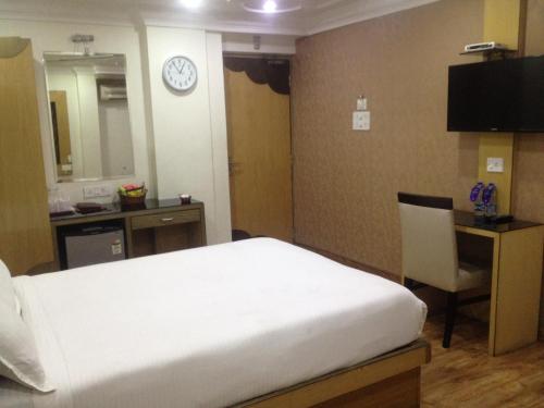 a bedroom with a bed and a desk and a clock at Ashreen Group of Hotels in Kolkata