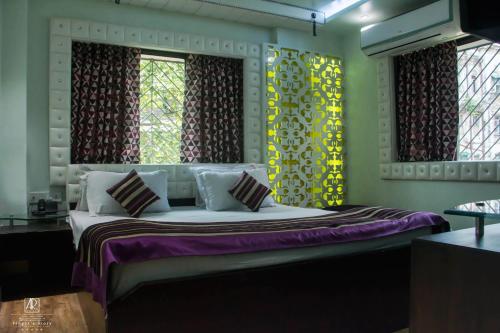a bedroom with a bed and two windows at Ashreen Group of Hotels in Kolkata