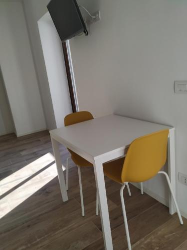 a white table and two yellow chairs in a room at Pause Lake Garda in San Giorgio