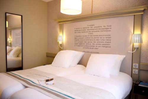 a hotel room with a white bed with a sign on the wall at Hôtel Littéraire Gustave Flaubert, BW Signature Collection in Rouen
