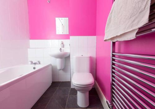 a pink bathroom with a toilet and a sink at Bright and Modern Causewayside Apartment in Edinburgh