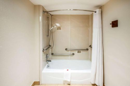 a bathroom with a shower and a white bath tub at Days Inn & Suites by Wyndham Tyler in Tyler