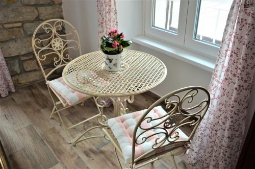 een tafel en stoelen met een vaas met bloemen erop bij Istrabella Apartment in Koper