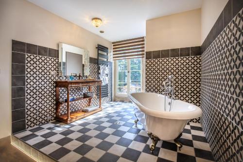 ein Badezimmer mit einer weißen Badewanne und einem Schachbrettboden in der Unterkunft Le Terminus in Tournus