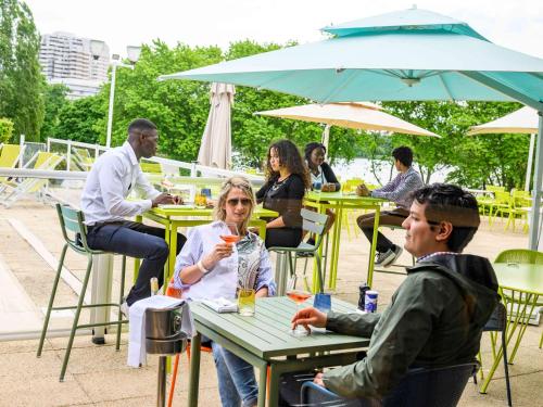 a group of people sitting at tables at an outdoor restaurant at Novotel Paris Créteil Le Lac in Créteil