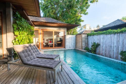 a chair sitting on a deck next to a swimming pool at Tango Luxe Beach Villa, Koh Samui in Choeng Mon Beach