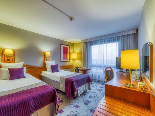 a hotel room with two beds and a television at Mercure Cieszyn in Cieszyn
