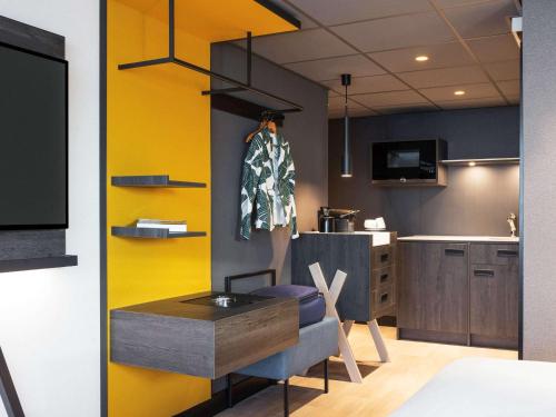 a kitchen with a yellow wall in a room at Mercure Amsterdam City Hotel in Amsterdam