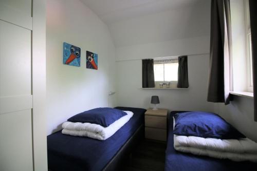 1 dormitorio con 2 camas con sábanas azules y ventana en De Witte Bergen 84, en IJhorst