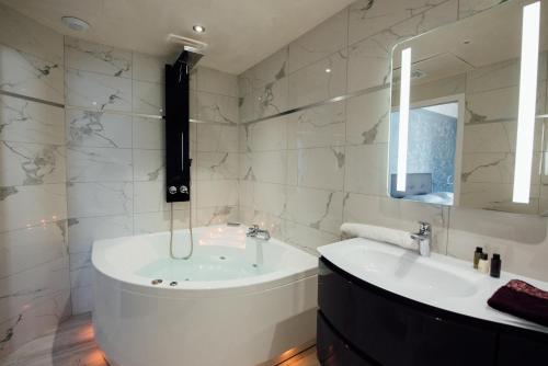 a bathroom with a tub and a sink and a mirror at Amirauté in La Baule