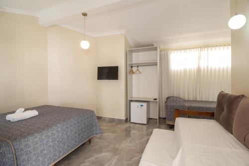 a hotel room with two beds and a couch at Pousada Espindola in Penha