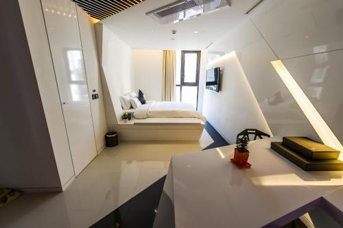 um pequeno quarto branco com uma cama e uma mesa em Hotel The Designers Jongro em Seul