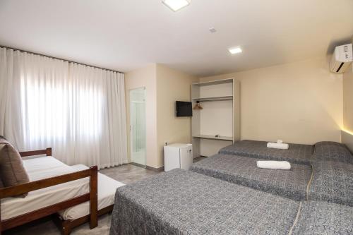 a hotel room with two beds and a window at Pousada Espindola in Penha