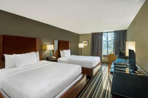 a hotel room with two beds and a television at Travelodge by Wyndham Memphis Airport/Graceland in Memphis