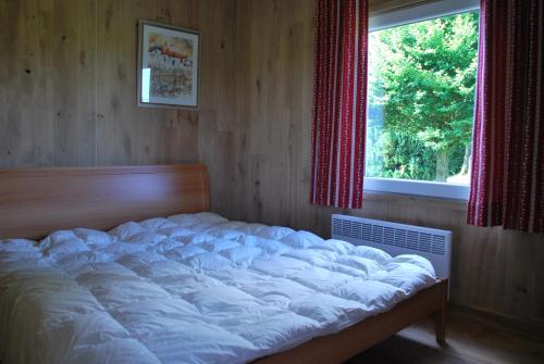 ein großes Bett in einem Zimmer mit Fenster in der Unterkunft Le Chalet à Bonnerue in Houffalize