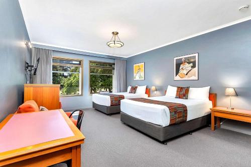 a hotel room with two beds and a desk at Quality Inn O'Connell in Adelaide