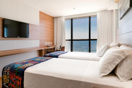 um quarto de hotel com duas camas e uma televisão em Arena Copacabana Hotel no Rio de Janeiro
