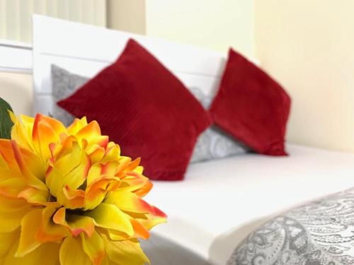 two red pillows and a yellow flower on a bed at Edinburgh Ocean Inn in Edinburgh