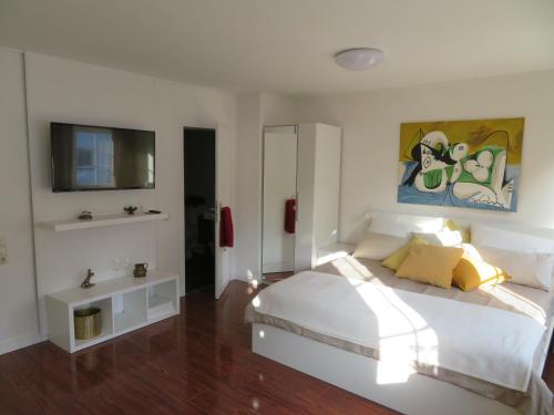 1 dormitorio con 1 cama blanca y TV en Ferienapartment Hugos, en Balve