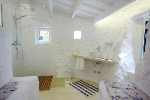 La salle de bains blanche est pourvue d'un lavabo et d'une douche. dans l'établissement S'Olivera, à Alaior