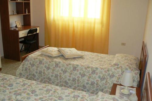een slaapkamer met een bed en een bureau en een tafel met een lamp bij Mariangela's Home in Carbonia