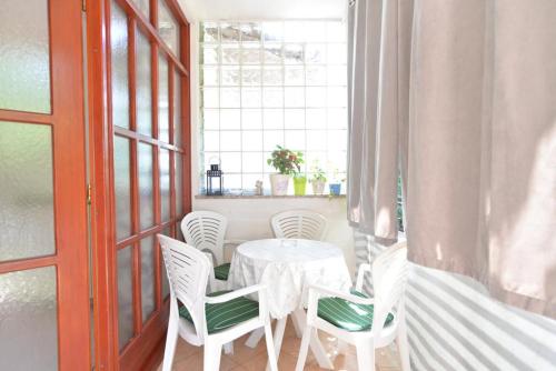 ein weißer Tisch und Stühle in einem Raum mit einem Fenster in der Unterkunft Apartman Snježana in Fažana