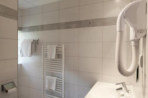 een witte badkamer met een douche en een wastafel bij Hotel Restaurant Faller Emmebuckel in Itterswiller