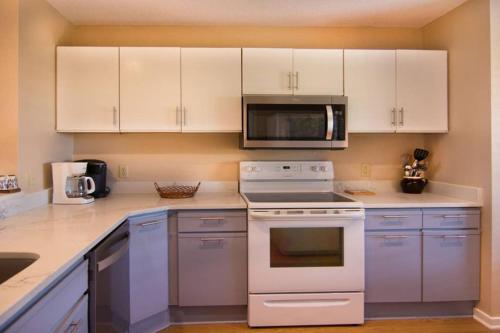 a kitchen with white cabinets and a stove and microwave at Pelican Point Unobstructed Beach Views Beach Access out back door! in Harbor Island