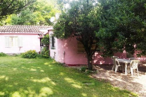 ein rosafarbenes Haus mit einem Tisch und Stühlen im Hof in der Unterkunft Hamacas Serranas in Salsipuedes