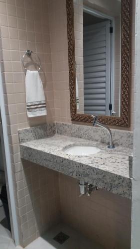 a bathroom with a sink and a mirror at Villagio Aloha Beach in Bertioga