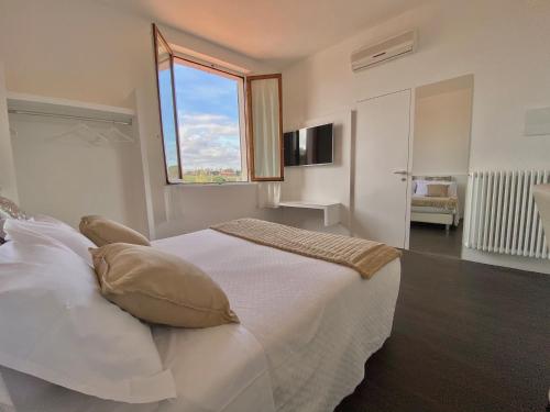 a bedroom with a large white bed with a window at Soggiorno Lo Stellino in Siena
