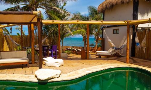 
a beach with a pool, chairs, and a tub at El Pez a Colibri Boutique Hotel in Tulum
