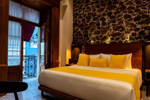 een slaapkamer met een groot bed met gele kussens bij Casa de la Luz Hotel Boutique in Mexico-Stad