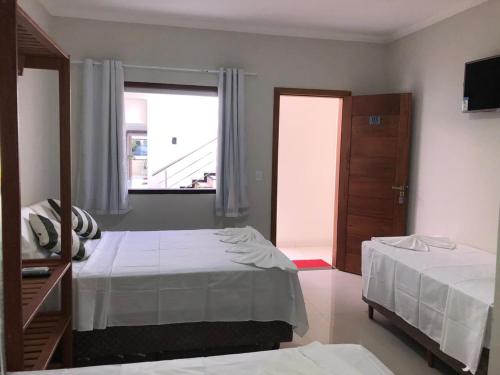 a hotel room with two beds and a window at Pousada Veleiro in Porto Seguro