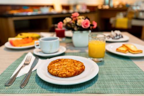 a table with plates of food and a glass of orange juice at Hotel Ponta Negra Beach Natal in Natal